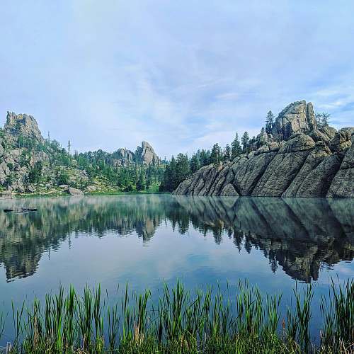 nature landscape photography of calm body of water surrounded by rocky mountains crazy horse